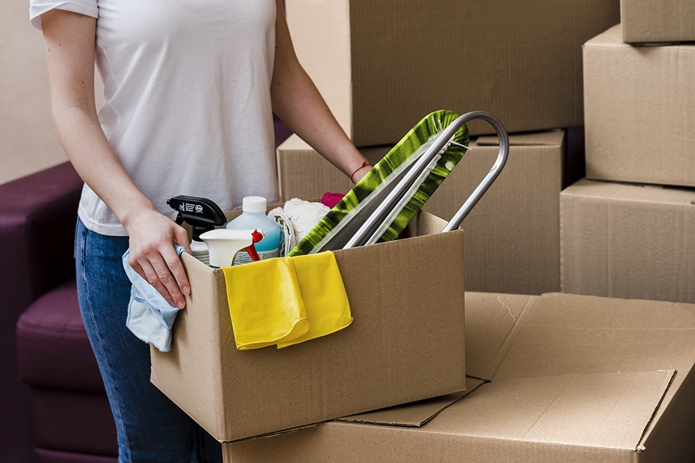 Femme avec des affaires de ménage dans un déménagement