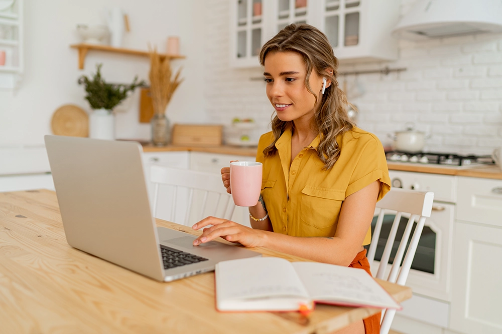 Femme en train de travailler chez elle dans la cuisine bien rangée