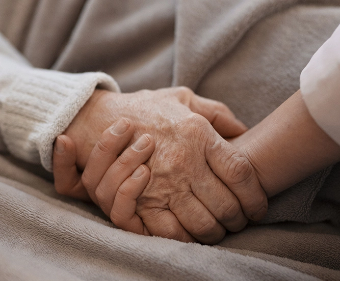 Main d'une personne âgée tenue par une aide